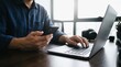 © TheseusStock - Man multitasking on laptop and smartphone in a modern office setting