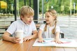 © Olha Tsiplyar - Siblings Talking Together at Cafe Table with Book, Family Connection