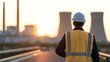 © photo for everything - Engineer in safety vest and hard hat look at industrial power plant complex at sunset. Professional supervisor inspect power facility outdoor