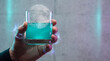 © wirachut - Halloween neon cyberpunk poison cocktails glowing turquoise drink held in hand with eerie futuristic mood