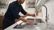 © Akbradob - Asian man washing and cleaning the stainless steel sink in a modern kitchen