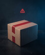 © Victoriia - Cardboard delivery box with a glowing red warning triangle representing a shipping problem or suspicious package alert