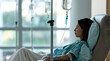 © Audrey - A patient in a clinic chair receives an IV infusion, with a drip visible in the background, indicating chemotherapy treatment