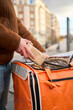 © Oscar - Courier preparing food order for delivery in thermal bag