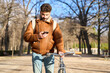 © Oscar - Man checking smartphone while walking bicycle in urban park