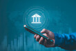 © Krittamet - Banking, Economic, digital finance, financial services, technology and connectivity. Global banking, finance, smartphone with a digital bank icon, world map and financial data.