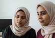 © Pixel-Shot - Diversity and inclusion in the workplace, two muslim women collaborating on a project in a modern office environment with focus and professional teamwork