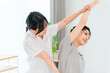 © buritora - 整体師,トレーナーの指導で肩と腕のストレッチをする女性