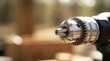 © Chaiwit - Close up of cordless drill chuck and metal bit against blurred workshop background, showing precision craftsmanship and active construction work