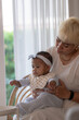 © ultramansk - Nurturing interracial parents cradle and feed their baby at home by a bright garden window, full of gentle care and love with a clean modern aesthetic perfect for family and lifestyle.