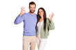 © deagreez - Photo of optimistic couple stand show okey wear sweater pants isolated on beige color background