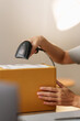 © Natee Meepian - Cropped hand scanning barcode label on cardboard box for e-commerce order fulfillment