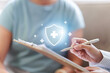© Natee Meepian - Healthcare protection concept with doctor writing on clipboard and shield graphic