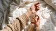 © Roshan - Flat lay perspective of hands spraying fragrance on wrist over white textured linen bed sheets, ideal for luxury lifestyle branding and social media stock