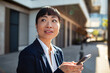 © Davor - Businesswoman using smartphone on city street