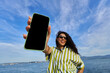 © Alvaro Lavin/Stocksy - Woman holding smartphone with blank screen outdoors