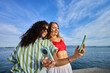 © Alvaro Lavin/Stocksy - Diverse friends taking selfie with smartphones by the sea