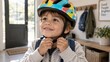© Natallia Simanchyk - A young boy smiles while fastening the chin strap of his colorful bicycle helmet inside a home entryway.