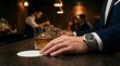 © Nathaniel - Businessman with wrist watch resting hand on bar counter with whiskey glass