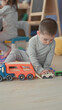 © Krakenimages.com - Little boy holds toy car with both hands while playing beside a transport truck in a playroom; curiosity bonding.