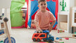 © Krakenimages.com - Boy places small toy truck and cars with his hand on the floor in a playroom inside a building; concentration imagination childhood.