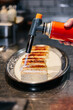 © Nibuya Qubik/Stocksy - Chef caramelizing dessert with torch
