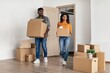 © Prostock-studio - Focused African American Male And Female Couple Carrying Boxes While Moving Into New Home, Showing Excitement And Teamwork In Living Room, Inviting Environment. Business Concept.