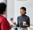 © Lumos sp - Portrait of two young business woman having a meeting or presentation and seminar standing in the office. Portrait of a young business woman talking