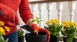 © Hryhor Denys - Person wearing red gloves holding a trowel with soil. Indoor gardening with potted plants and white railing.