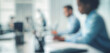 © dwi - Blurred image of a busy office environment showing diverse professionals working on laptops, focusing on productivity and collaboration.