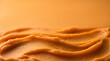 © Tetiana - Close up of smooth pureed orange pumpkin spread in wavy strokes with soft lighting and wide empty space for text top view macro