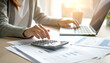 © Sina Ettmer - Gemütlicher Arbeitsplatz im Homeoffice mit Laptop, Finanzdiagrammen und Taschenrechner