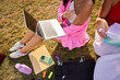 © Alvaro Lavin/Stocksy - Students learning outdoors using laptop on grass
