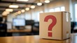 © MSTMAYA - Cardboard box with a large red question mark printed on the side sitting on a wooden desk in a blurred modern office environment background