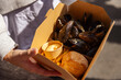 © Francis - Steamed mussels with french fries, dip sauce, and bread served in takeaway cardboard box, person holding street food meal image with copy space for text, fast seafood gastronomy dining concept.