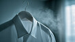 © Daria - White dress shirt hanging on a wooden hanger with steam rising in soft natural light creating an elegant and fresh fabric care scene