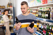 © JackF - Interested positive man making purchases in grocery store, buying bottle beer