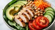 © Maryna - Vibrant bowl filled with fresh chicken salad ingredients. Slices of avocado sit near grilled white meat strips. Bowl holds lemon cucumber tomatoes chickpea and carrot shreds for healthy eating.