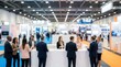 © Wannaeka - Active business exhibition featuring people networking at brightly lit information booths.
