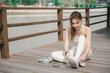 © sorapop - Female runner and sport athlete shows sharpened determination during preparation for outdoor fitness exercise, tying shoelaces on wooden bridge with headphones and smartphone nearby