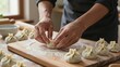 © mihrzn - A chef meticulously folds dough to form classic khinkali dumplings on a wooden board dusted with flour.