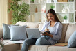 © PheelingsMedia - Happy telecommuter writing notes in paper agenda working at home