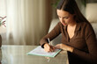 © PheelingsMedia - Serious woman is filling out paper form on a coffee table