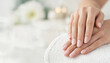 © SerPak - Well-groomed hands with soft pink manicured nails rest gently on a white towel in a bright, tranquil beauty setting with copy space.
