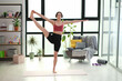 © H_Ko - Fit woman practices standing in yoga balance in bright home interior. Athlete holds raised leg extending arm while maintaining steady body control
