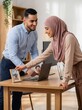 © Agus Through Lens - Happy modern muslim couple setting up photo frame on desk in home office remote work concept