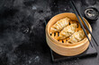 © Mironov - Steamed Korean Dumplings with pork meat and vegetables in bamboo steamer. black background. top view