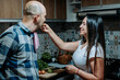 © LuisPimenttel - Couple enjoying a playful moment in the kitchen as the woman feeds her partner, representing love, companionship and shared everyday life.