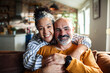 © Marko Geber - Smiling mature couple hugging on sofa at home
