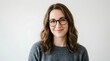 © Jakia - Portrait of smiling young woman with wavy brown hair wearing round black glasses and gray sweater against plain light background, natural soft lighting, headshot